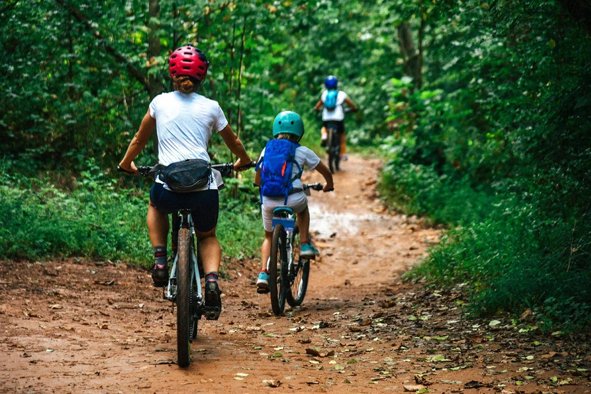 An outdoor scene with a family enjoying mountain biking along a dirt path surrounded by trees, capturing the joy and togetherness of outdoor family outings.