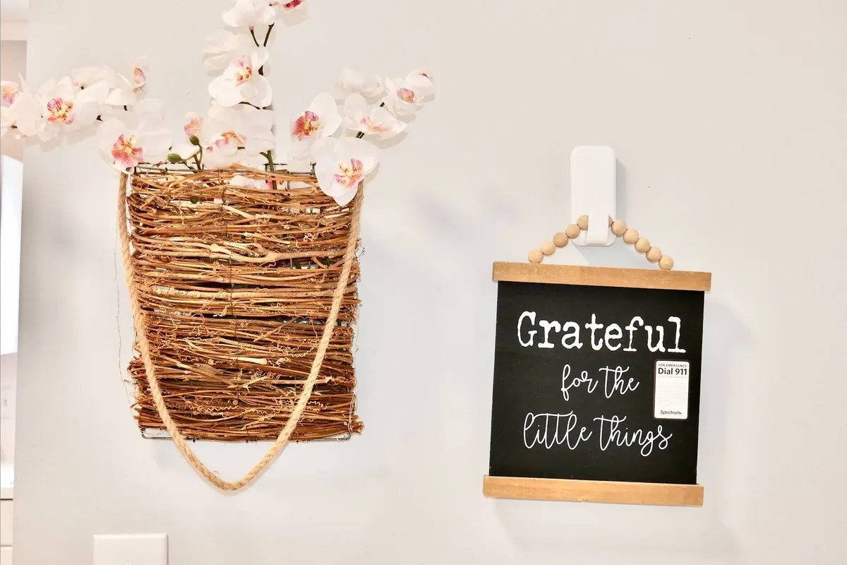 A close-up of a woven basket filled with fresh flowers placed beside a chalkboard sign with an uplifting message. The setting suggests a welcoming, homey environment, ideal for guests arriving for special occasions or family gatherings.