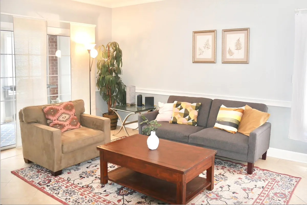 A cozy and spacious living area with a comfortable sofa, coffee table, armchair, decorative plants, and wall art. The room is inviting and ideal for relaxation, social gatherings, or unwinding after a day of adventure.