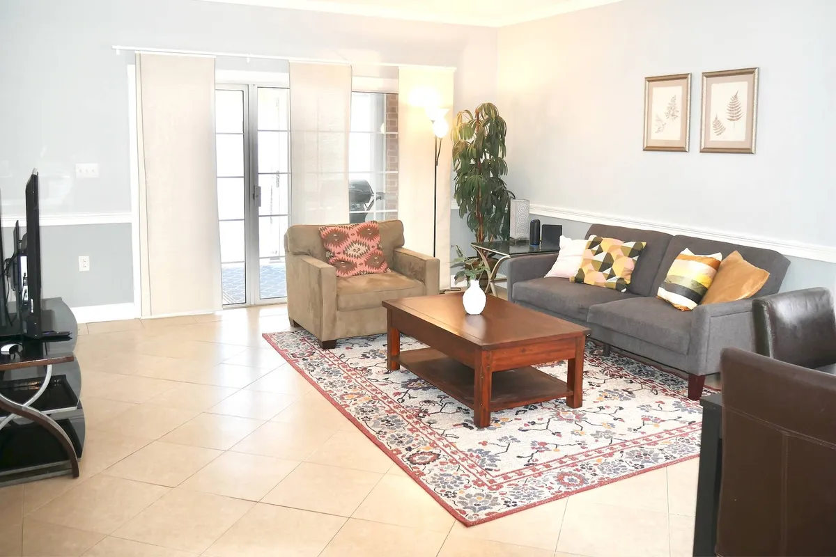 A stylish living room with a comfortable sofa, modern coffee table, decorative plant, and contemporary artwork on the wall. The scene is bright and welcoming, with space for group gatherings or winding down after an exciting night out.