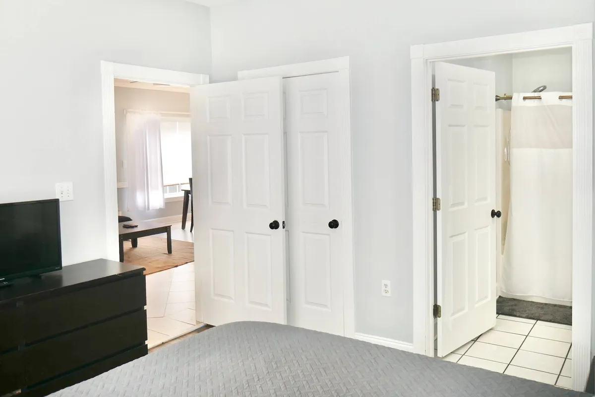 A cozy bedroom with a plush bed, nightstand, and TV, complemented by soothing lighting and inviting decor. The bedroom doors open into the space, suggesting easy access for families to relax and gather after a day of exploration.